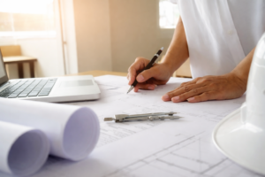 Engenheiro analisando projeto estrutural em planta técnica sobre mesa de trabalho